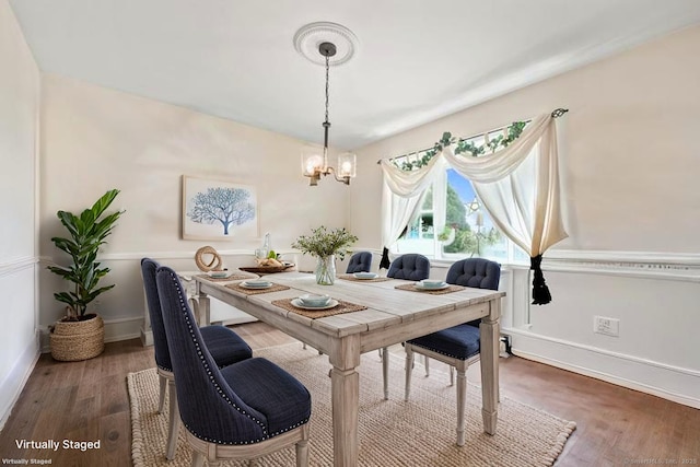 dining area with a chandelier, wood finished floors, and baseboards