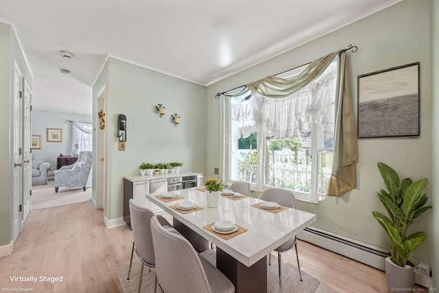 dining room with a baseboard heating unit, light wood-style flooring, crown molding, and baseboards