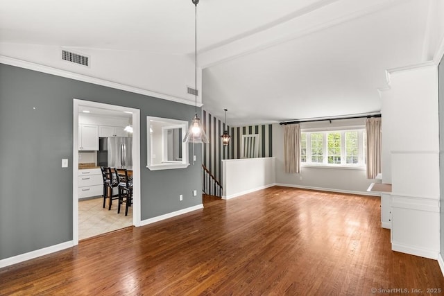 unfurnished living room with wood finished floors, visible vents, and vaulted ceiling with beams