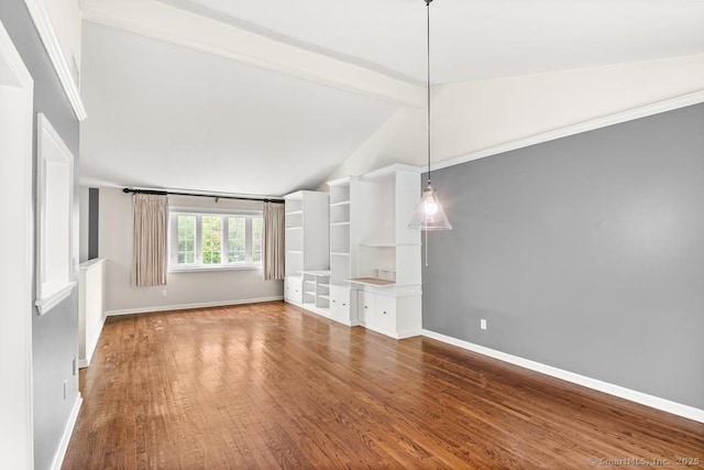 interior space featuring wood finished floors, baseboards, and vaulted ceiling with beams