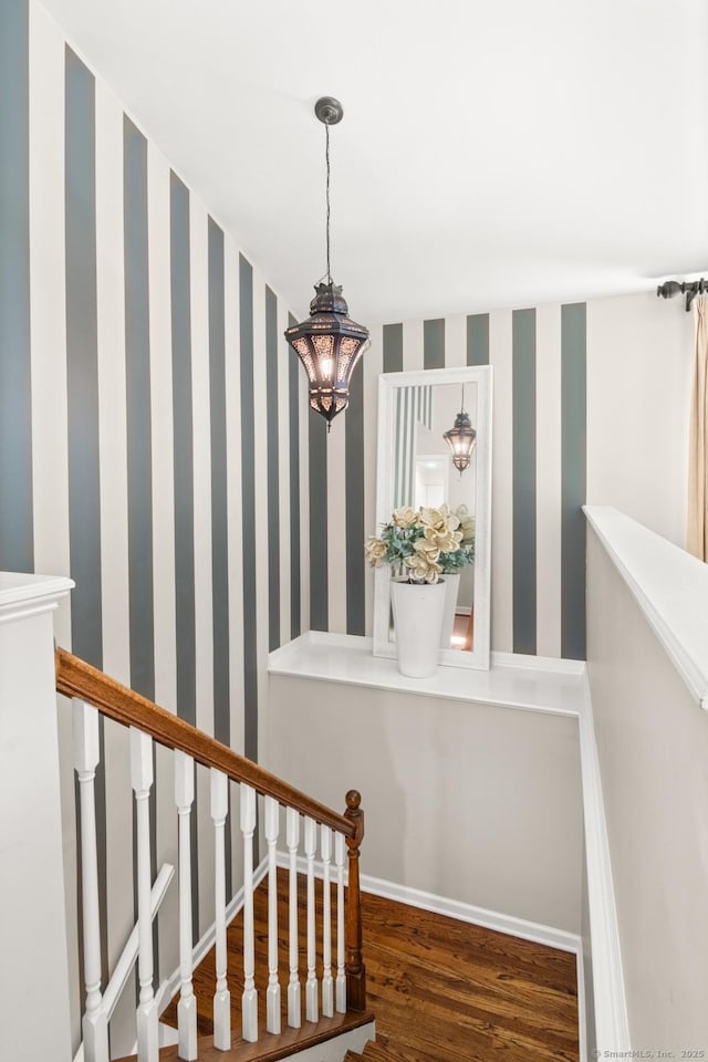 stairs with baseboards, wallpapered walls, and wood finished floors