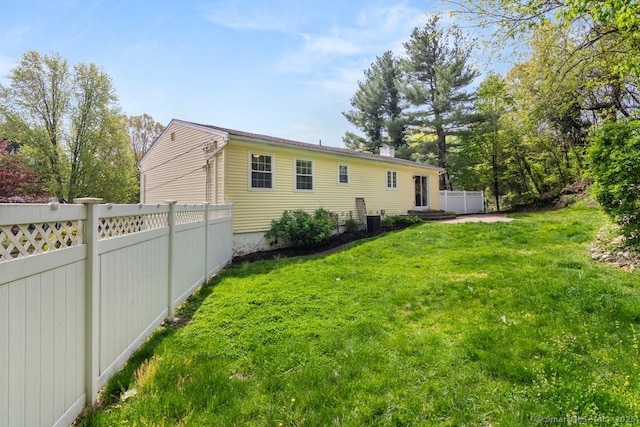 view of side of property with cooling unit, a yard, and fence