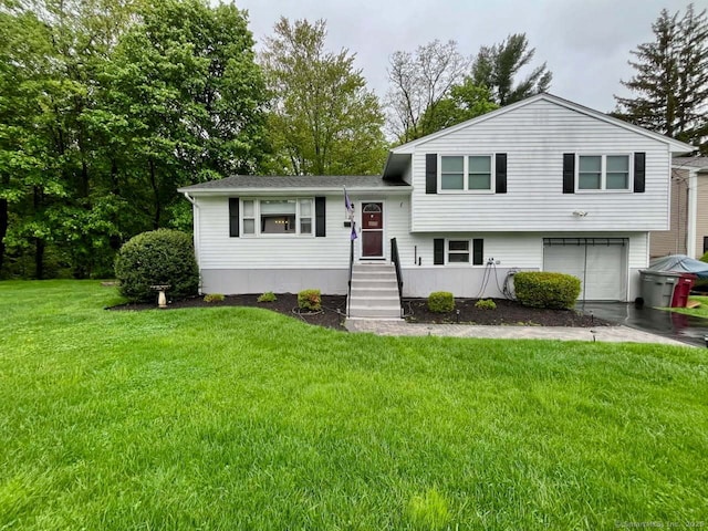 split level home with an attached garage, a front yard, and a shingled roof