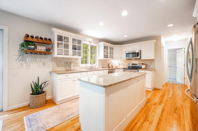 45 Wolf Pit Rd, Southbury, CT 06488 - kitchen featuring stainless steel appliances, decorative backsplash, light wood-style floors, white cabinetry, and a kitchen island