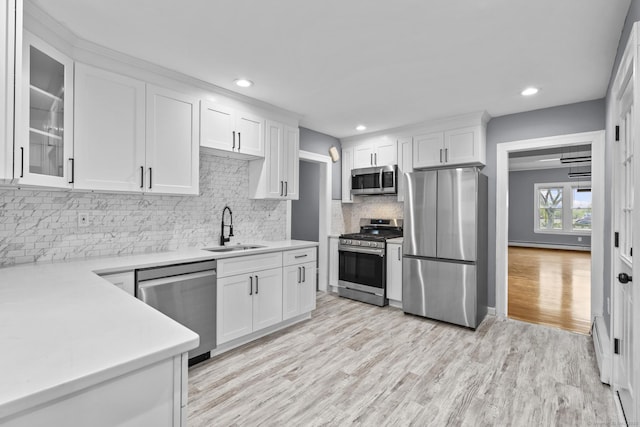 181 Westbourne Pkwy, Hartford, CT 06112 - kitchen featuring a sink, white cabinets, light wood-type flooring, backsplash, and appliances with stainless steel finishes