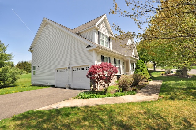 view of side of property with a shingled roof, an attached garage, a yard, and aphalt driveway