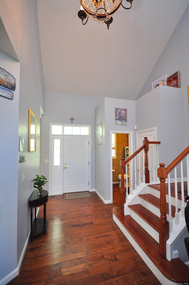 foyer with high vaulted ceiling, baseboards, hardwood / wood-style floors, and a notable chandelier