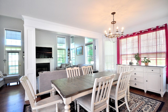 dining area featuring crown molding, dark wood-style flooring, an inviting chandelier, and plenty of natural light
