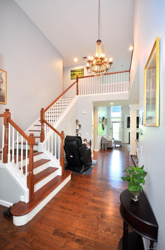 entryway featuring visible vents, stairway, wood-type flooring, a chandelier, and a high ceiling