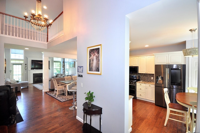 interior space featuring a high ceiling, black appliances, dark wood-style flooring, and open floor plan