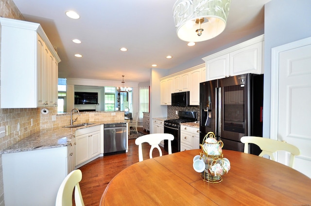 kitchen with dark wood-style flooring, a sink, recessed lighting, decorative backsplash, and black appliances