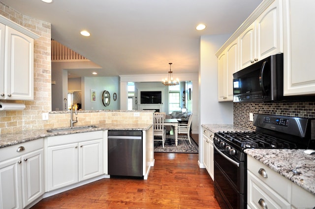 kitchen featuring decorative backsplash, dark wood-style flooring, a sink, black appliances, and a peninsula