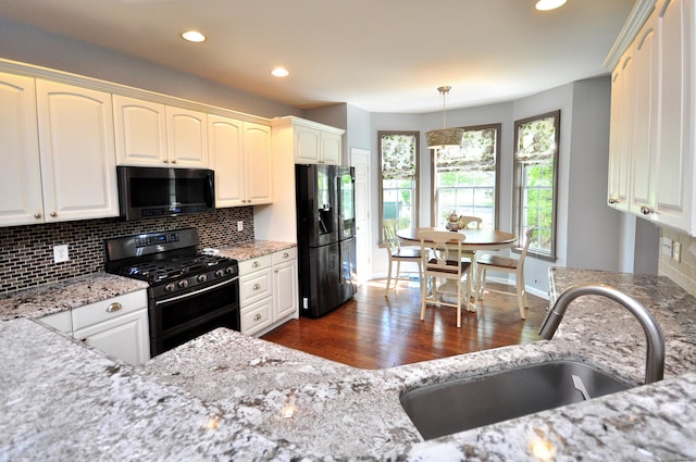 kitchen with decorative backsplash, a sink, black appliances, and dark wood-type flooring