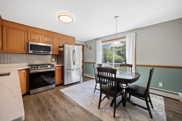 54 Silo Dr, Wethersfield, CT 06109 - kitchen with stainless steel appliances, baseboard heating, light countertops, dark wood-style flooring, and brown cabinetry