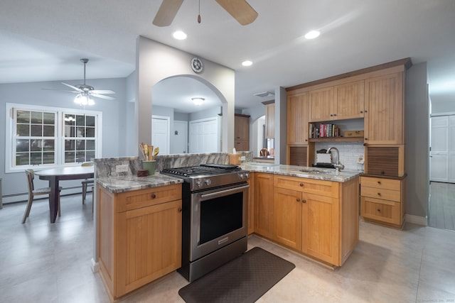 kitchen with stainless steel gas range, light stone countertops, ceiling fan, and a sink