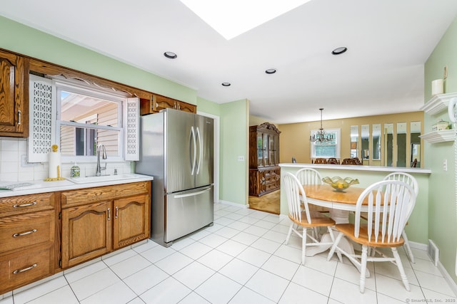 250 Glenn Dr, Stratford, CT 06614 - kitchen featuring freestanding refrigerator, a sink, brown cabinets, light countertops, and a chandelier