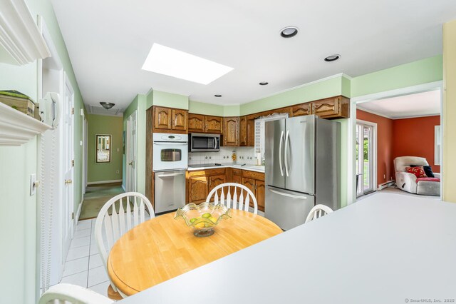 250 Glenn Dr, Stratford, CT 06614 - kitchen with stainless steel appliances, a skylight, light countertops, light tile patterned floors, and brown cabinets