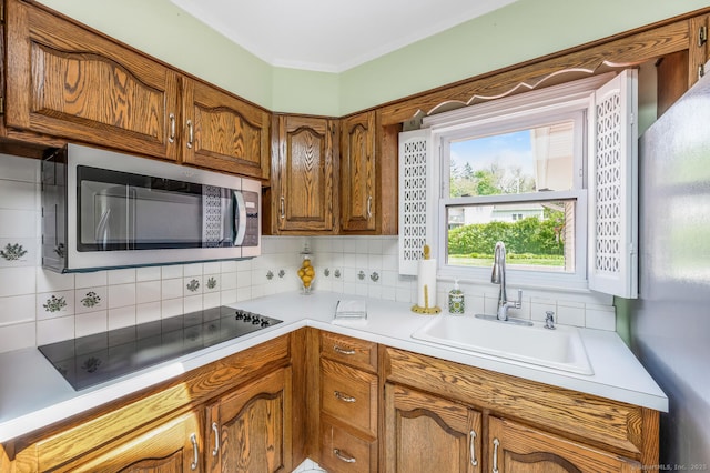 250 Glenn Dr, Stratford, CT 06614 - kitchen featuring stainless steel microwave, a sink, black electric stovetop, freestanding refrigerator, and tasteful backsplash