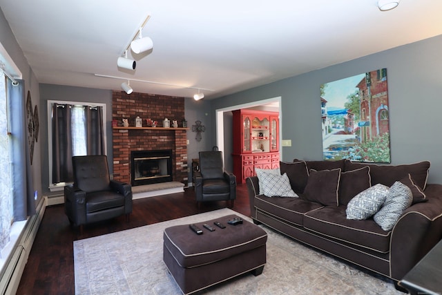 living area with a baseboard heating unit, a brick fireplace, and wood finished floors