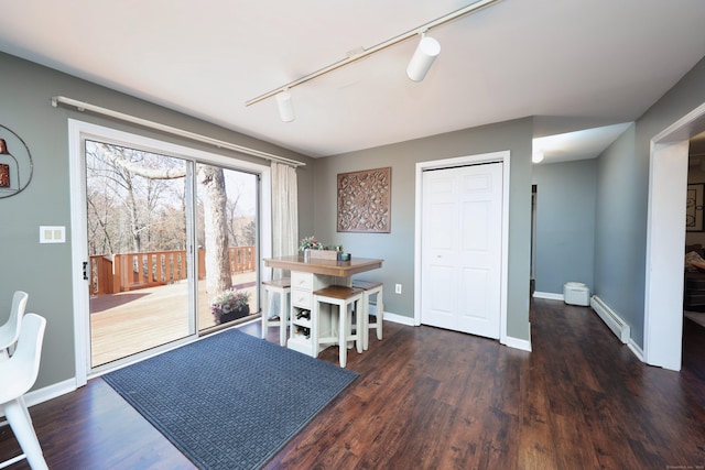 dining space with rail lighting, baseboards, baseboard heating, and wood finished floors