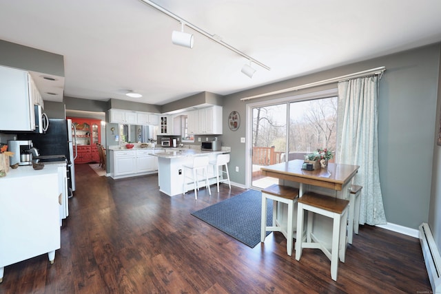 dining room with a baseboard heating unit, baseboards, rail lighting, and dark wood-type flooring
