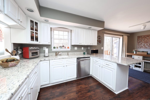 kitchen with a sink, a peninsula, white cabinets, and appliances with stainless steel finishes
