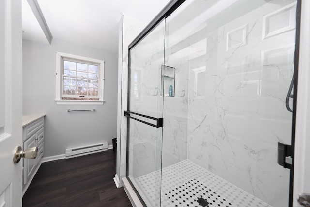 bathroom with a marble finish shower, wood finished floors, baseboards, and a baseboard heating unit