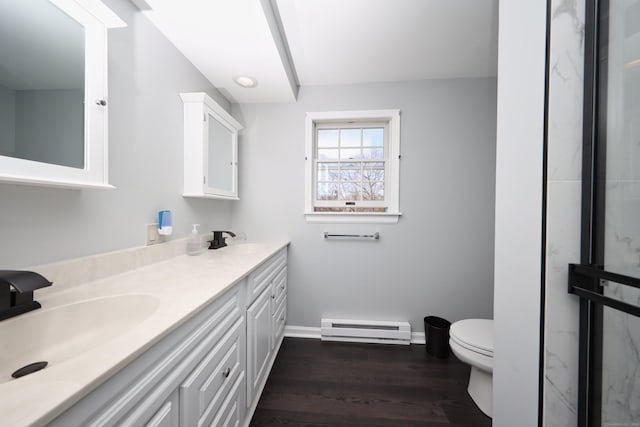 full bathroom featuring toilet, baseboard heating, a sink, and wood finished floors