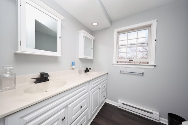 bathroom with double vanity, baseboards, a baseboard radiator, and a sink