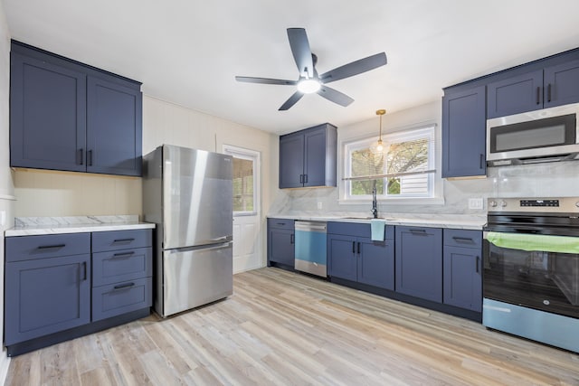 kitchen with ceiling fan, decorative backsplash, blue cabinetry, stainless steel appliances, and light wood-type flooring