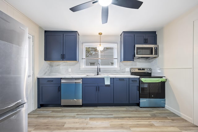 kitchen featuring appliances with stainless steel finishes, decorative backsplash, blue cabinetry, and a sink