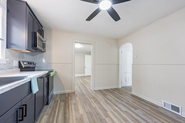 kitchen with stainless steel appliances, visible vents, arched walkways, light countertops, and light wood-type flooring