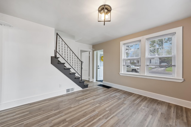 foyer entrance with stairway, baseboards, visible vents, and wood finished floors