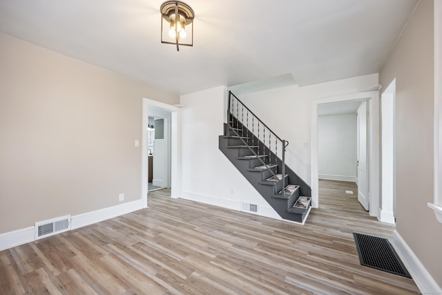 unfurnished living room with stairway, visible vents, and wood finished floors