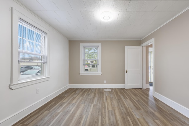empty room featuring baseboards, light wood finished floors, and crown molding