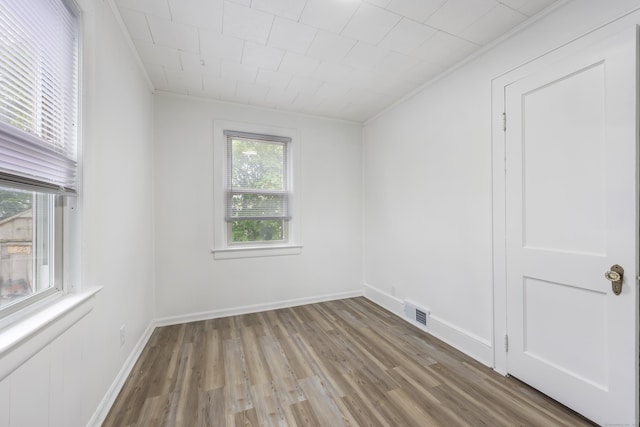 empty room featuring baseboards, visible vents, and wood finished floors