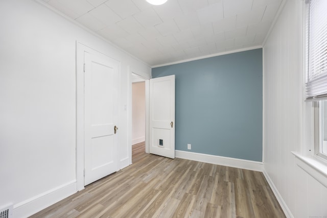 unfurnished bedroom featuring ornamental molding, baseboards, visible vents, and light wood-style floors