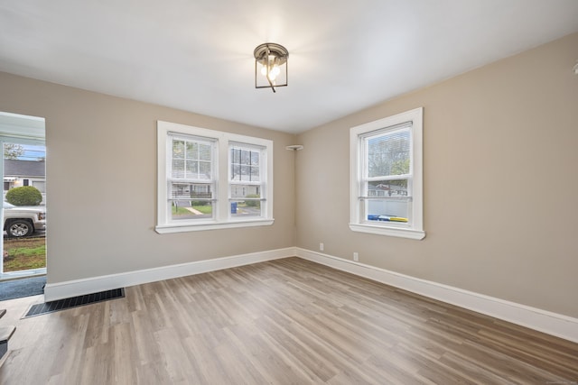 empty room featuring visible vents, plenty of natural light, and wood finished floors