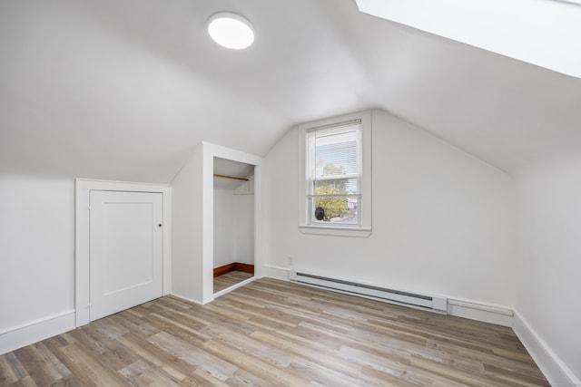 bonus room featuring light wood finished floors, vaulted ceiling, baseboards, and a baseboard radiator