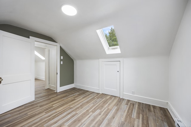 bonus room with baseboards, wood finished floors, lofted ceiling with skylight, and a baseboard heating unit