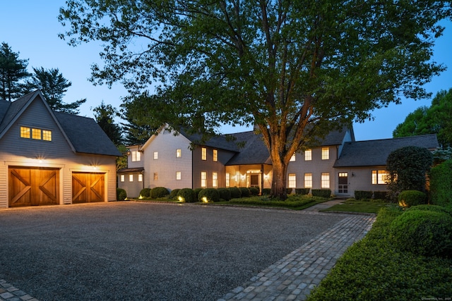 945 Oenoke Rdg, New Canaan, CT 06840 - view of front of property with a garage, gravel driveway, an outbuilding, and roof with shingles