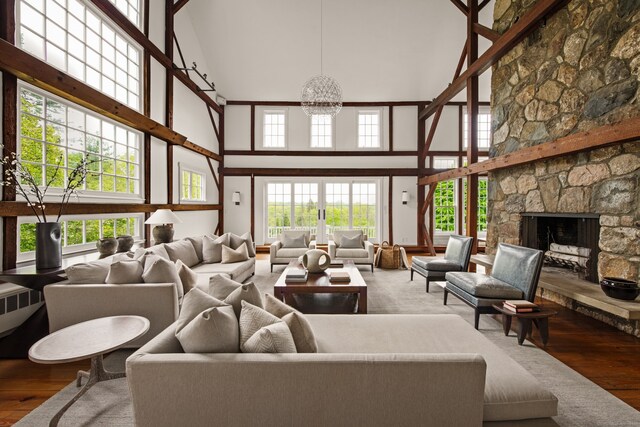 945 Oenoke Rdg, New Canaan, CT 06840 - living room featuring a high ceiling, wood finished floors, a chandelier, a stone fireplace, and plenty of natural light