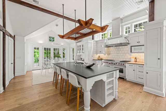 945 Oenoke Rdg, New Canaan, CT 06840 - kitchen with range with two ovens, open shelves, wall chimney range hood, a sink, and dark countertops