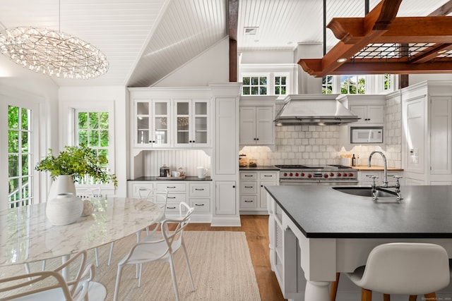 945 Oenoke Rdg, New Canaan, CT 06840 - kitchen featuring a sink, dark countertops, lofted ceiling, plenty of natural light, and light wood-style floors
