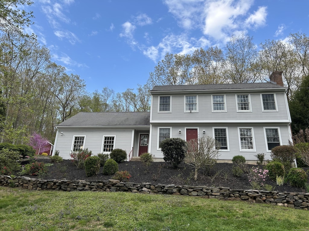 colonial inspired home featuring a front lawn and a chimney