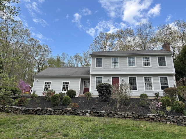 colonial inspired home featuring a front lawn and a chimney