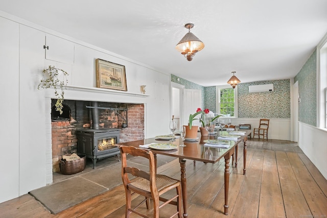 455 E St, Middletown, CT 06457 - dining room featuring a wood stove, hardwood / wood-style flooring, wallpapered walls, an AC wall unit, and wainscoting