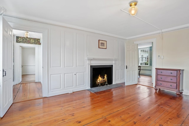 455 E St, Middletown, CT 06457 - unfurnished living room featuring radiator, a fireplace with flush hearth, ornamental molding, and light wood-style flooring