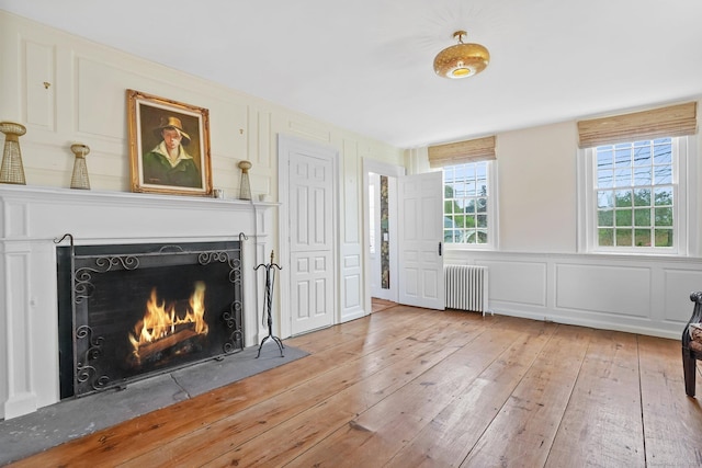 455 E St, Middletown, CT 06457 - unfurnished living room with radiator, hardwood / wood-style floors, a fireplace with flush hearth, and a decorative wall