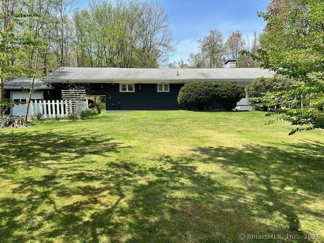 rear view of property with fence, a chimney, and a lawn